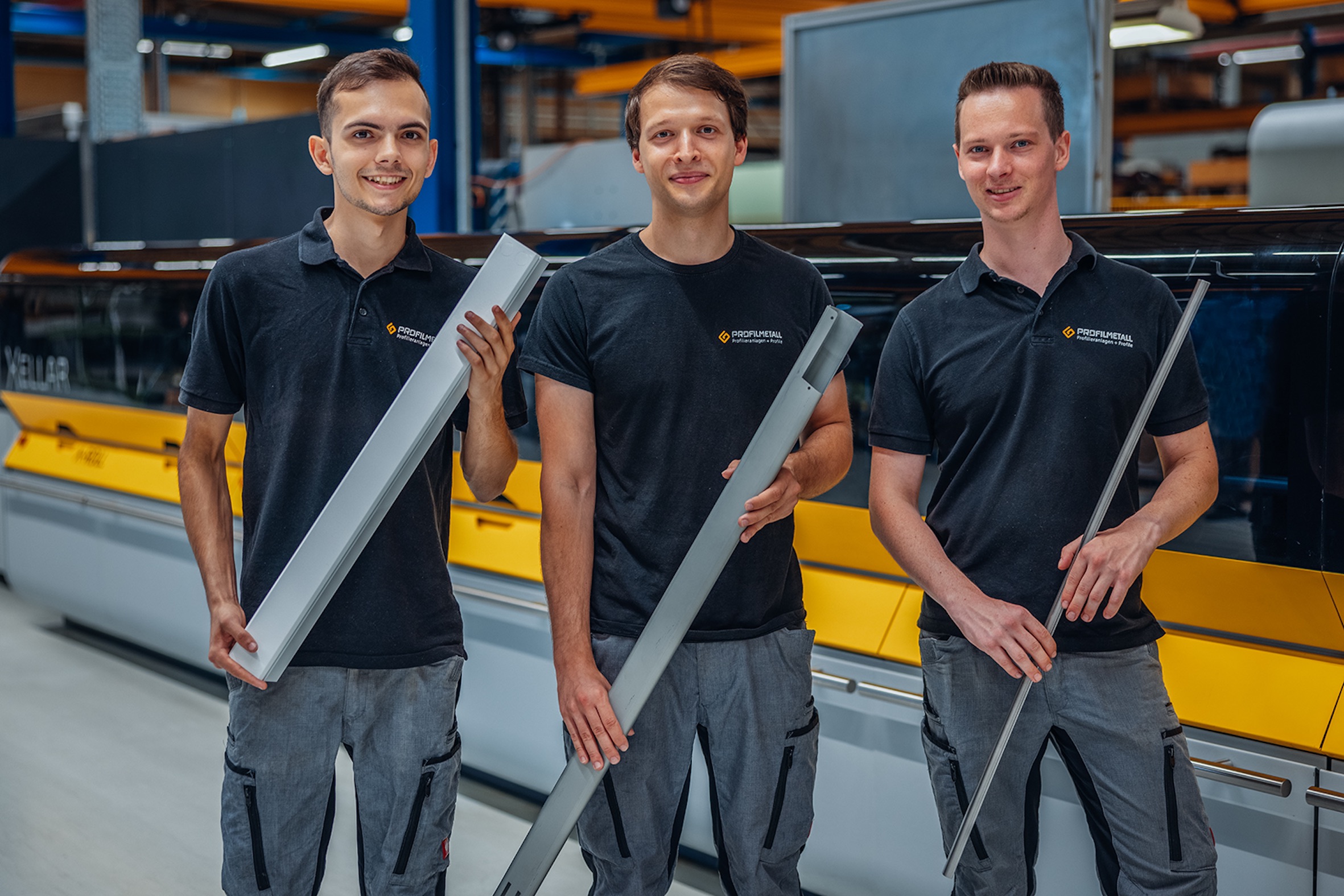 Profilmetall employees with profiles in front of a Xellar profiling line. The Group benefits from the demand for higher and high-strength steels in two ways: Profilmetall GmbH thanks to orders for contract manufacturing and Profilmetall Engineering GmbH thanks to orders for Xellar plants. © Profilmetall