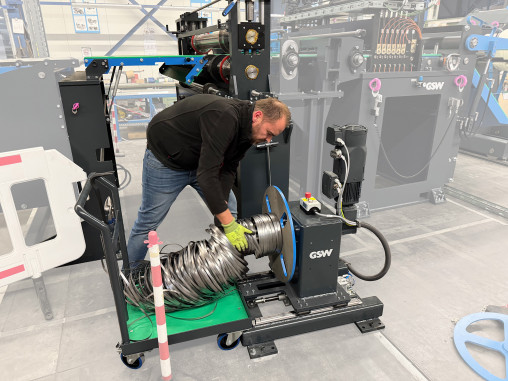 Der Saumschrott wird drehmomentgesteuert aufgewickelt, die Haspel ist konisch, so dass das Abziehen des Saumschrottcoils einfach ist. Da ein Kran nicht nutzbar war, dient ein passend konstruierter Wagen dem Abtransport. Im Hintergrund ist die Besäumschere zu sehen. © GSW