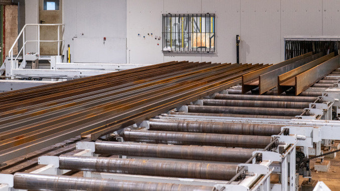 Die Beschickung der Split-Line bei Butzkies Stahlbau erfolgt im Materiallager im Außenbereich. Links ist die Belade- und Pufferzone zu sehen. Rechts werden zwei Sträger in die Strahlanlage transportiert. © Behringer