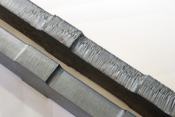 Links ist eine saubere, gratfreie Schnittkante, rechts zeigt sich eine typische Gratbildung mit Oxidationsverfärbungen. Das zeigt, wie Parameterführung und Gasmanagement die Ergebnisqualität beeinflussen. (CO2-Laser, Schneidgas Sauerstoff, Blechdicke circa 15 mm). © Rime